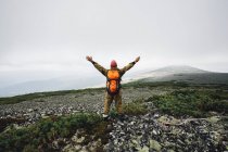 Rear view of man standing with arms outstretched on mountain — Stock Photo