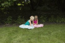 Schwestern sitzen auf Wiese im Hinterhof — Stockfoto