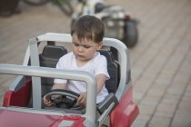 Carino ragazzo seduto in giocattolo auto all'aperto — Foto stock