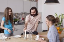 Lächelnde Familie arrangiert Esstisch in Küche — Stockfoto