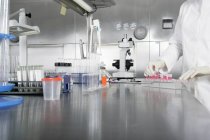 Vista a nivel de superficie de la mesa de laboratorio con persona usando tubos de ensayo - foto de stock