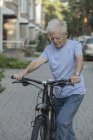 Senior man cycling on cobbled street in city — Stock Photo