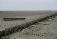 Краєвид туманного і плоскі пляж з покинутих човен на пляжі — стокове фото