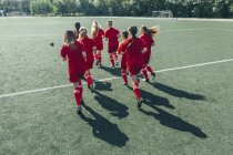 Rear view of female soccer players running on field — Stock Photo