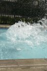 Éclaboussures d'eau dans la piscine le jour ensoleillé — Photo de stock