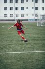 Determined teenager kicking ball on soccer field — Stock Photo