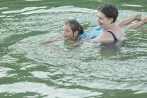 Grandmother teaching granddaughter swimming in lake — Stock Photo