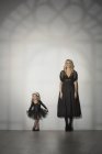Ritratto di madre e figlia in abiti neri in piedi contro il muro allo studio di danza — Foto stock