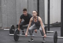 Male and female athlete exercising with barbells during crossfit training — Stock Photo