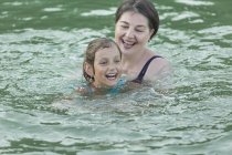 Cheerful grandmother and granddaughter swimming in lake — Stock Photo