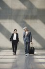 Confident business people with wheeled luggage walking at airport — Stock Photo