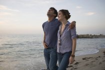 Couple marchant le long de la plage ensemble et riant — Photo de stock