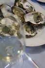 Placa de ostras crudas y copa de vino blanco - foto de stock