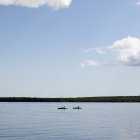 Отдаленный вид на двух человек в каноэ на идиллическом озере — стоковое фото