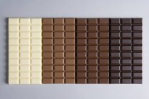 Row of various chocolate bars on grey background — Stock Photo