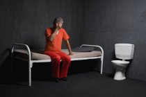 Sad prisoner sitting on bed in prison cell — Stock Photo