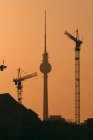 Guindastes de construção com silhueta de Alexanderplatz Television Tower no fundo — Fotografia de Stock