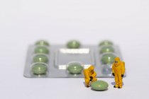 Невеликий вчених в чисті костюми обстеження зелені таблетки з Блістерна упаковка — стокове фото