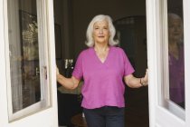 Retrato confiado mujer mayor de pie en la puerta del patio - foto de stock