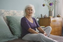 Portrait confiant femme âgée se détendre sur le lit — Photo de stock