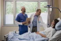 Medici che fanno il giro, parlano con il paziente nella stanza d'ospedale — Foto stock