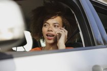 Молода жінка говорити на смарт-телефон і водіння автомобіля — стокове фото