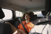 Mujer joven y cansada durmiendo en el asiento trasero del coche - foto de stock