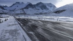Amoncellement de neige sur une route distante sous la neige couvert de montagnes, champ de glace Columbia, Alberta, Canada — Photo de stock