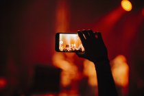 Hand of man in audience video recording concert with camera phone — Stock Photo
