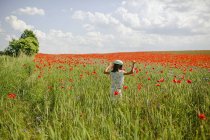 Girl running in sunny, idyllic rural red poppy field — Stock Photo