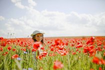 Girl in sunny, idyllic rural red poppy field — Stock Photo