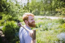 Hombre sonriente con barba sosteniendo la pala en el soleado jardín — Stock Photo