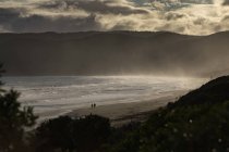 Пара силуэтов прогуливаясь по спокойному пляжу на закате солнца, Aireys Inlet, Виктория, Австралия — стоковое фото