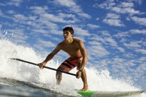 Молодой человек на вёслах катается на океанской волне — стоковое фото