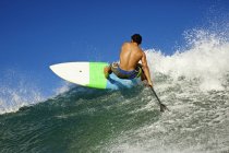 Junger, fitter Mann paddelt auf Ozeanwelle — Stockfoto