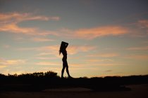 Silhouette di donna sulla spiaggia al tramonto — Foto stock
