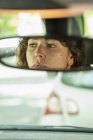 Reflection of woman in rear-view mirror driving car — Stock Photo