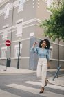 Retrato de mujer feliz y despreocupada cruzando la calle de la ciudad - foto de stock