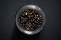 Vista dall'alto grani di pepe neri in vaso di spezie — Foto stock
