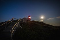 Faro illuminato sotto il cielo notturno della luna piena, Norddorf, Schleswig Holstein, Germania — Foto stock