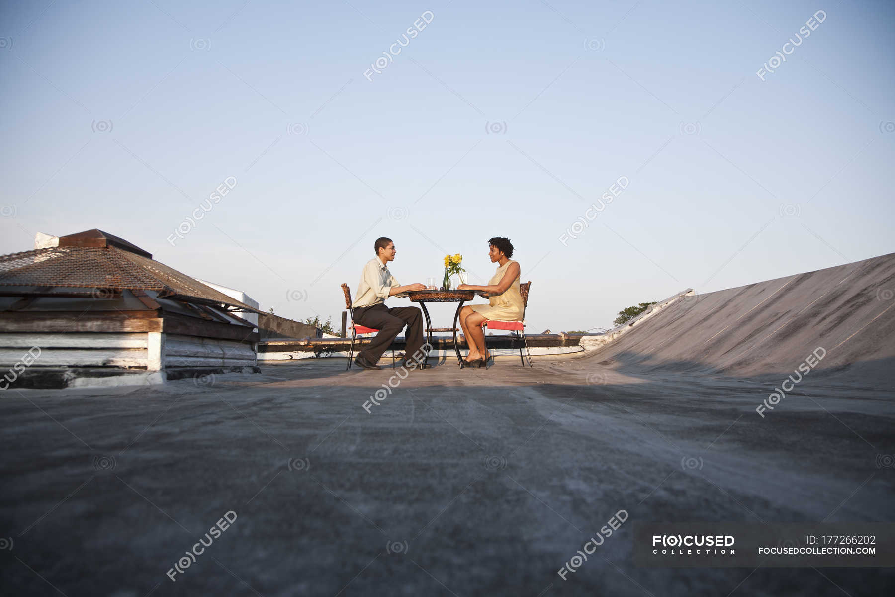 A Couple Eating A Meal On A Rooftop Terrace Short Hair Heterosexual Couple Stock Photo