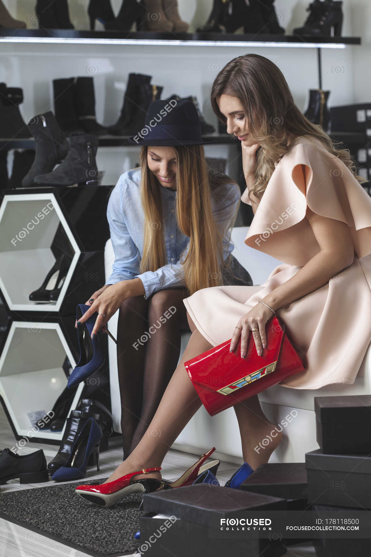 Female Friends Trying On High Heels At Store Buying Shelf