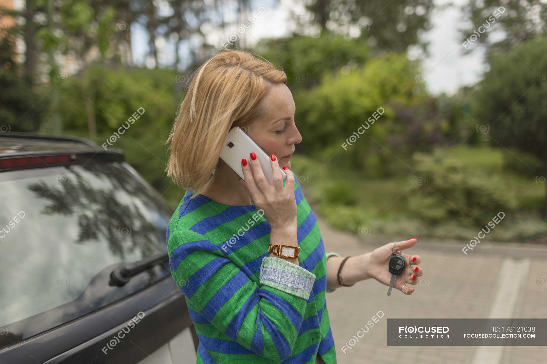 Mature Woman Holding Key While Talking On Mobile Phone Next