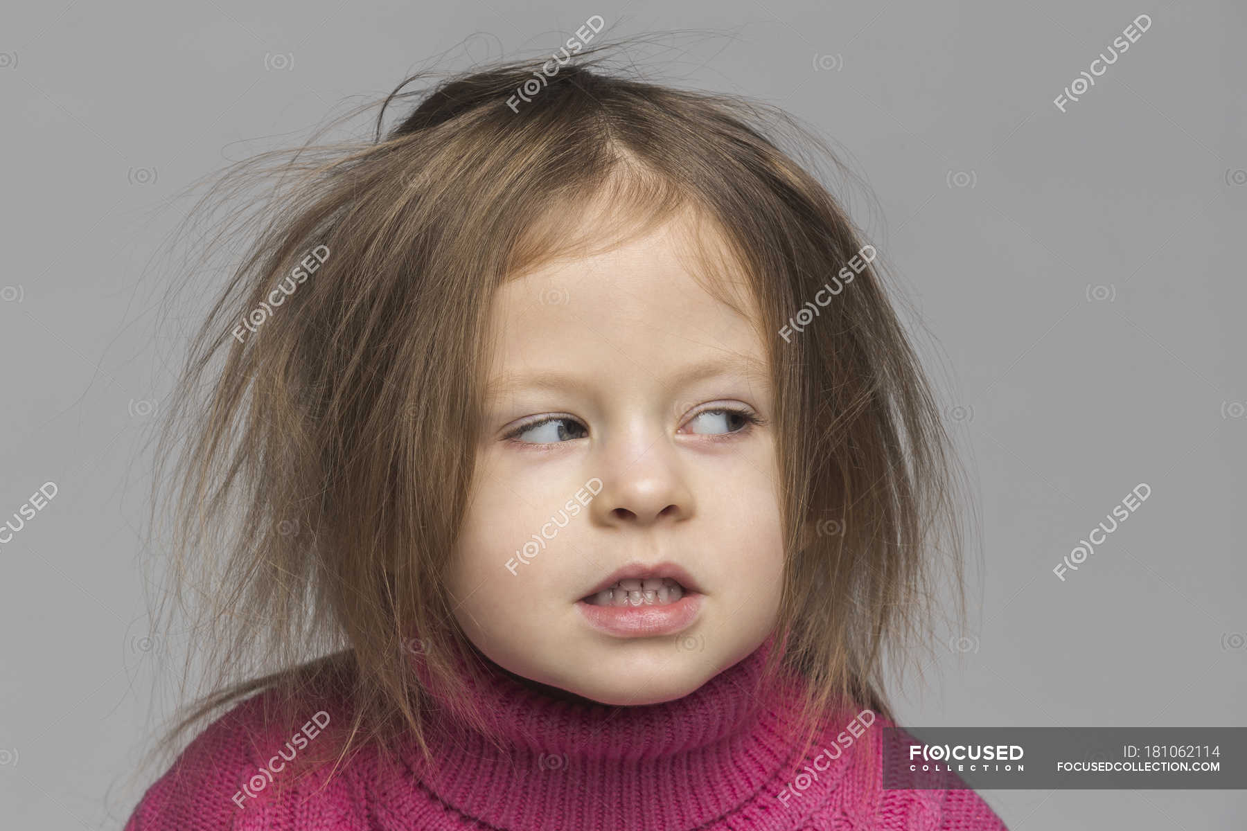 Portrait Of Cute Girl With Messy Hair Looking Away Against Gray