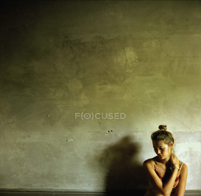 Una joven cruza los brazos contra una pared - foto de stock