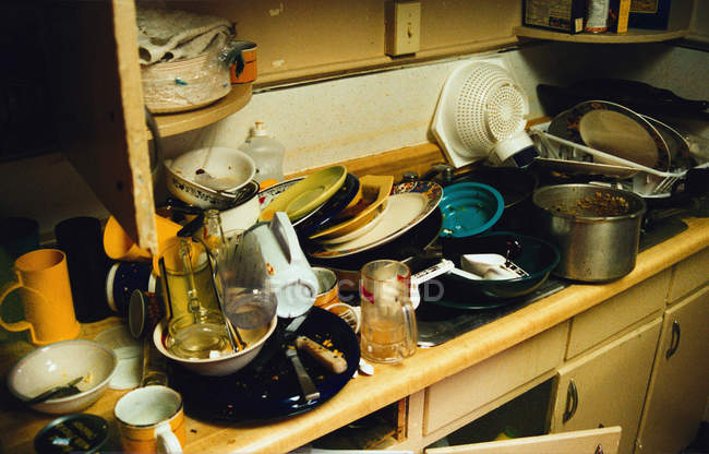 Vista en ángulo bajo de los utensilios de cocina sucios apilados en el fregadero en la cocina - foto de stock