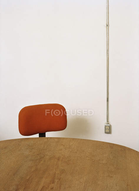 Cultivo mesa de madera y silla de oficina en el fondo de la pared blanca - foto de stock
