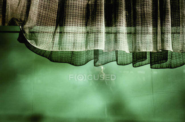 Cortinas de culturas penduradas sobre parede verde-iluminada — Fotografia de Stock