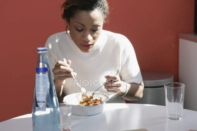 Mujer comiendo pasta para llevar - foto de stock