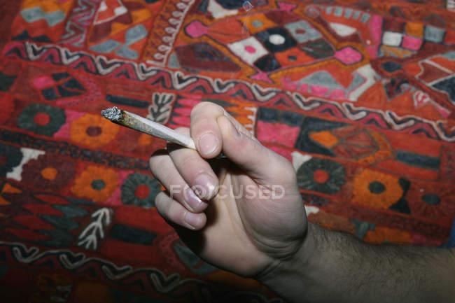 Crop main masculine tenant la cigarette roulée à la main avec de la marijuana — Photo de stock
